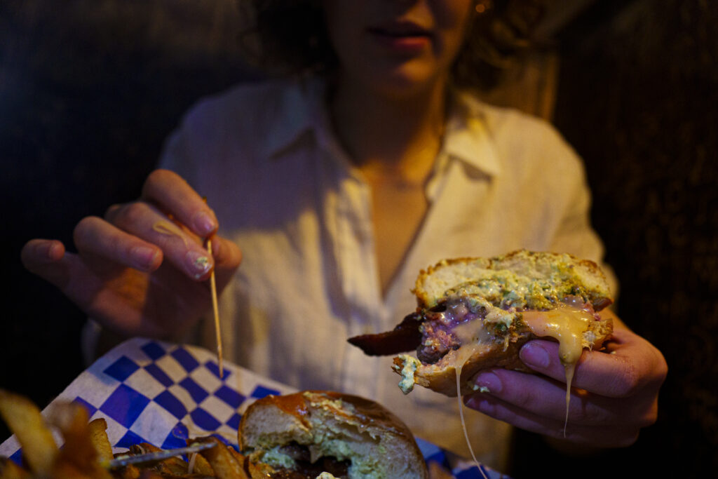 Aenea Keren eats a Jucy Lucy at Blue Door Pub located in Minneapolis on March 15, 2024. Photo by Maya Modelli